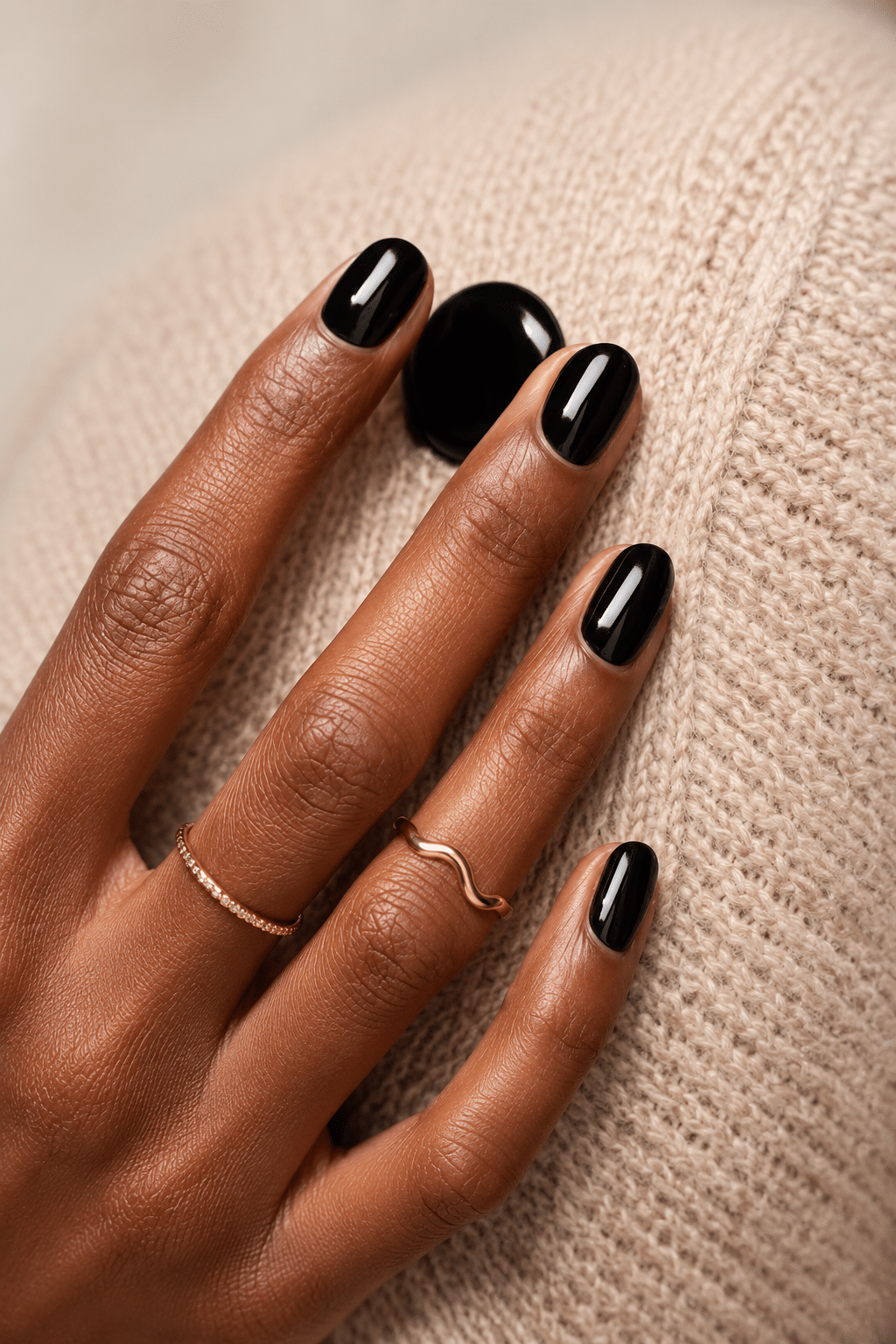 glossy black gel nail polish on deep skin tone