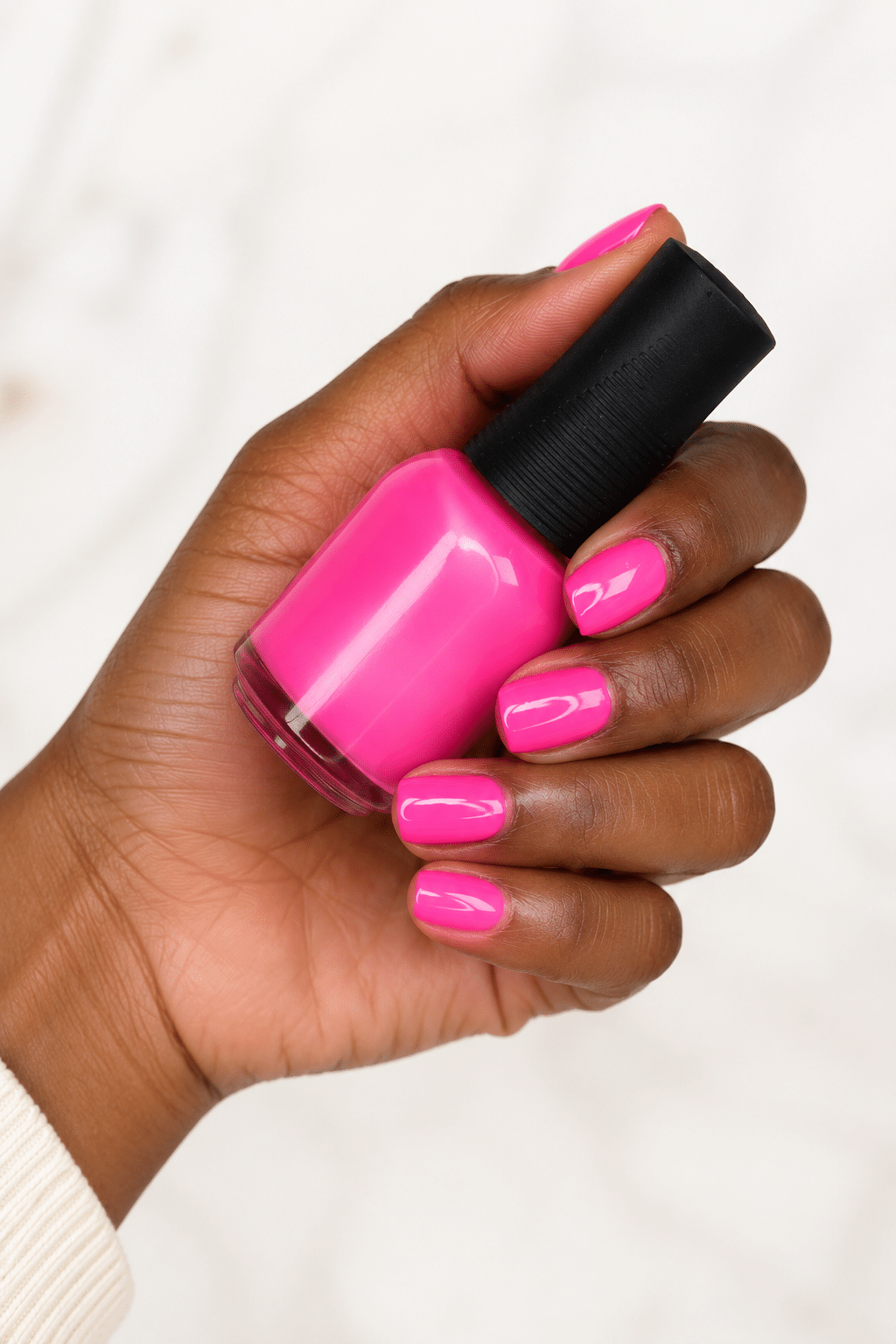 Neon pink nail varnish on deep skin with a glossy bold finish