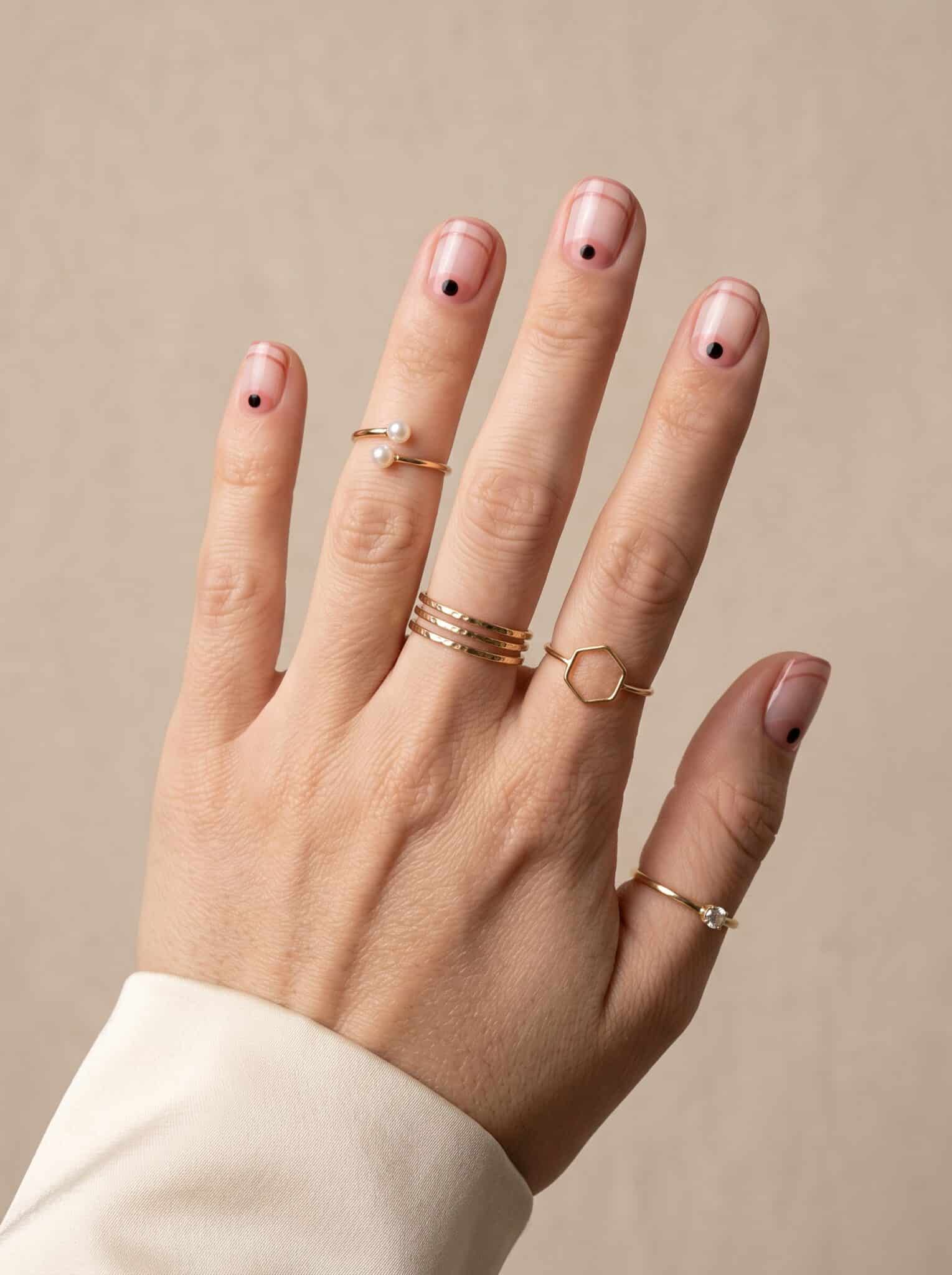 Sheer nude manicure with tiny green black and red tip details