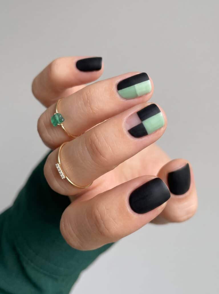 Short acrylic nails with black polish and slim green stripe accents