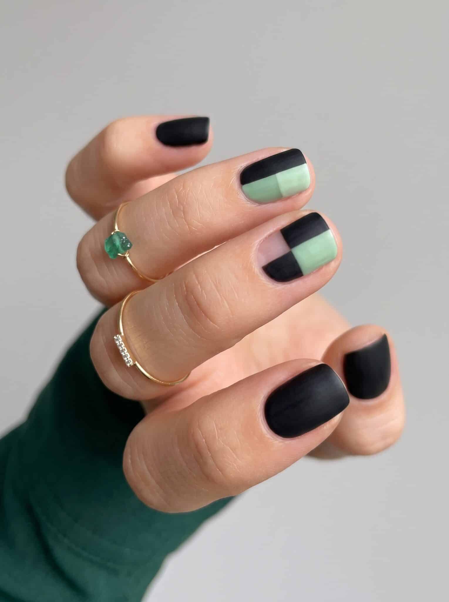 Short acrylic nails with black polish and slim green stripe accents