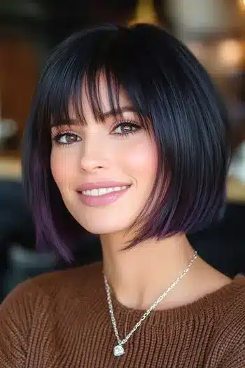 34 Sleek Bob Haircuts With Bangs That Feel Fresh and On-Trend 11 Blunt bob with piecey bangs and purple tips on a smiling woman, featured in 34 Sleek Bob Haircuts With Bangs That Are Totally On-Trend.