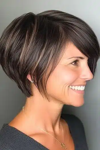 34 Sleek Bob Haircuts With Bangs That Feel Fresh and On-Trend 14 Pixie bob with side-swept bangs on a smiling woman, featured in 34 Sleek Bob Haircuts With Bangs That Are Totally On-Trend.