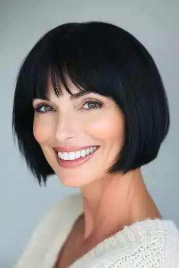 34 Sleek Bob Haircuts With Bangs That Feel Fresh and On-Trend 24 Jaw-Length Bob with Bangs Haircut on a smiling woman with black hair.
