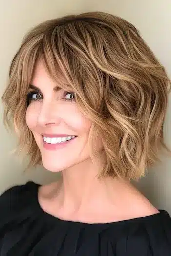 34 Sleek Bob Haircuts With Bangs That Feel Fresh and On-Trend 29 Wavy Blunt Bob with Curtain Bangs Haircut on a smiling woman with brown hair.